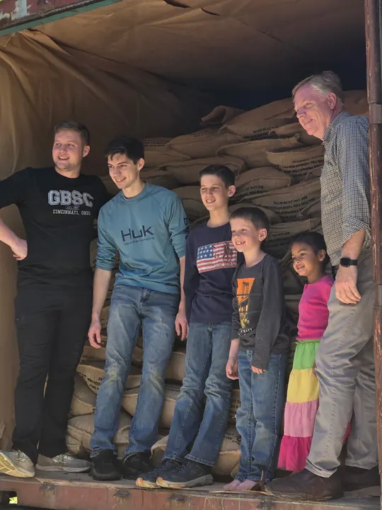 People standing in a shipping container with stacked coffee sacks