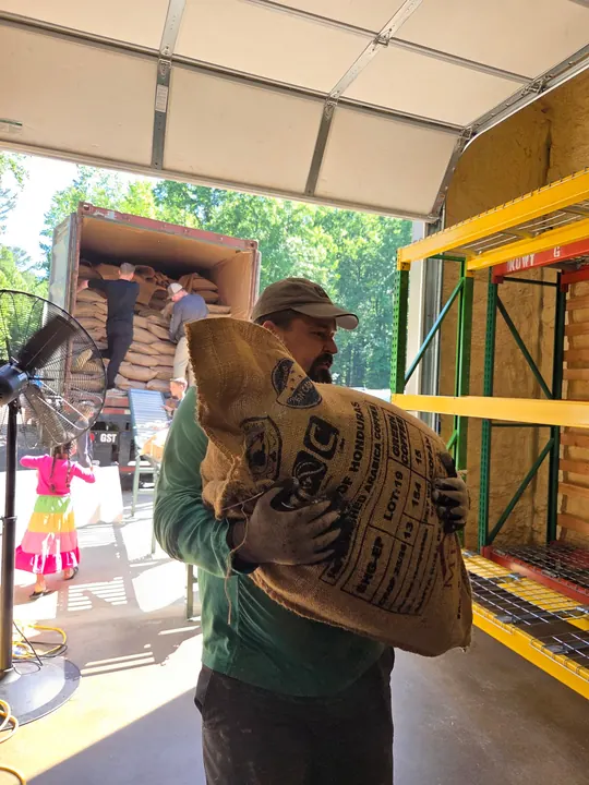 A person carrying a burlap coffee sack inside the roastery