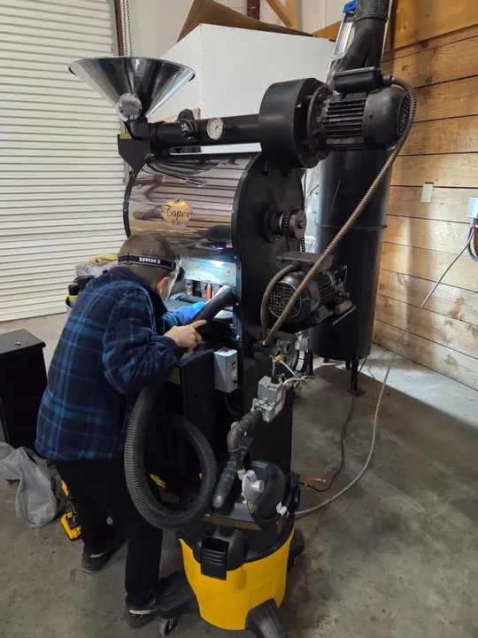 A child helping clean roastery equipment