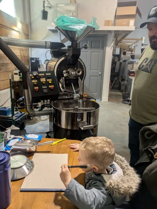 A child sitting near a table in the Brotherhood Coffee roastery